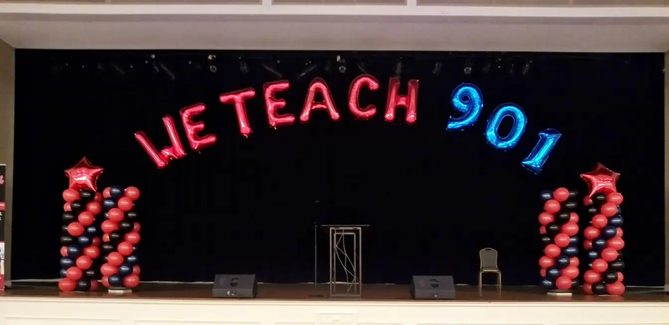 Pink balloon letters spelling out a welcome across a stage