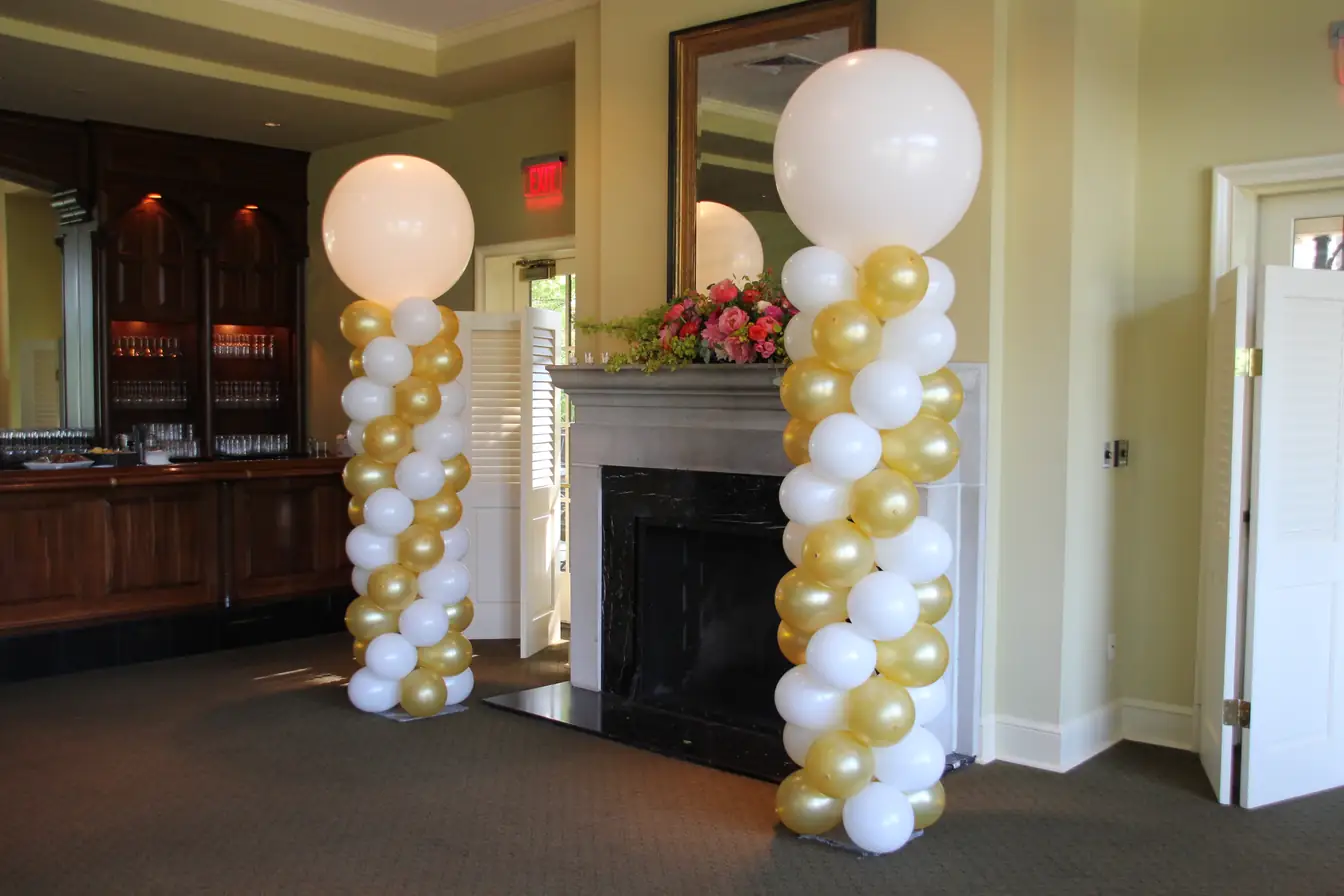 Gold and white balloon columns flanking a fireplace with topper balloons