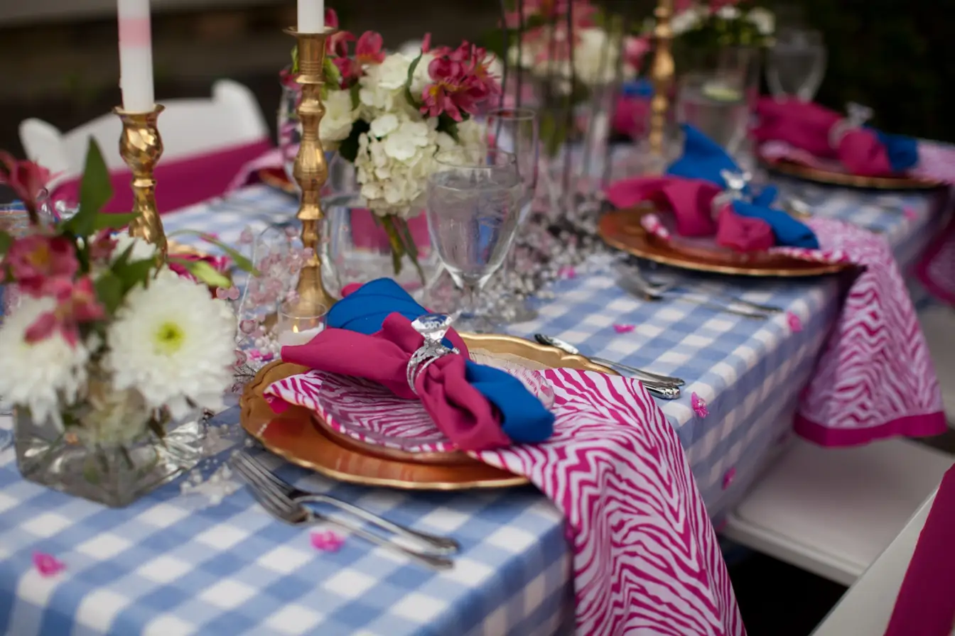 Gold charger plate with pink and blue napkins on a blue gingham linen