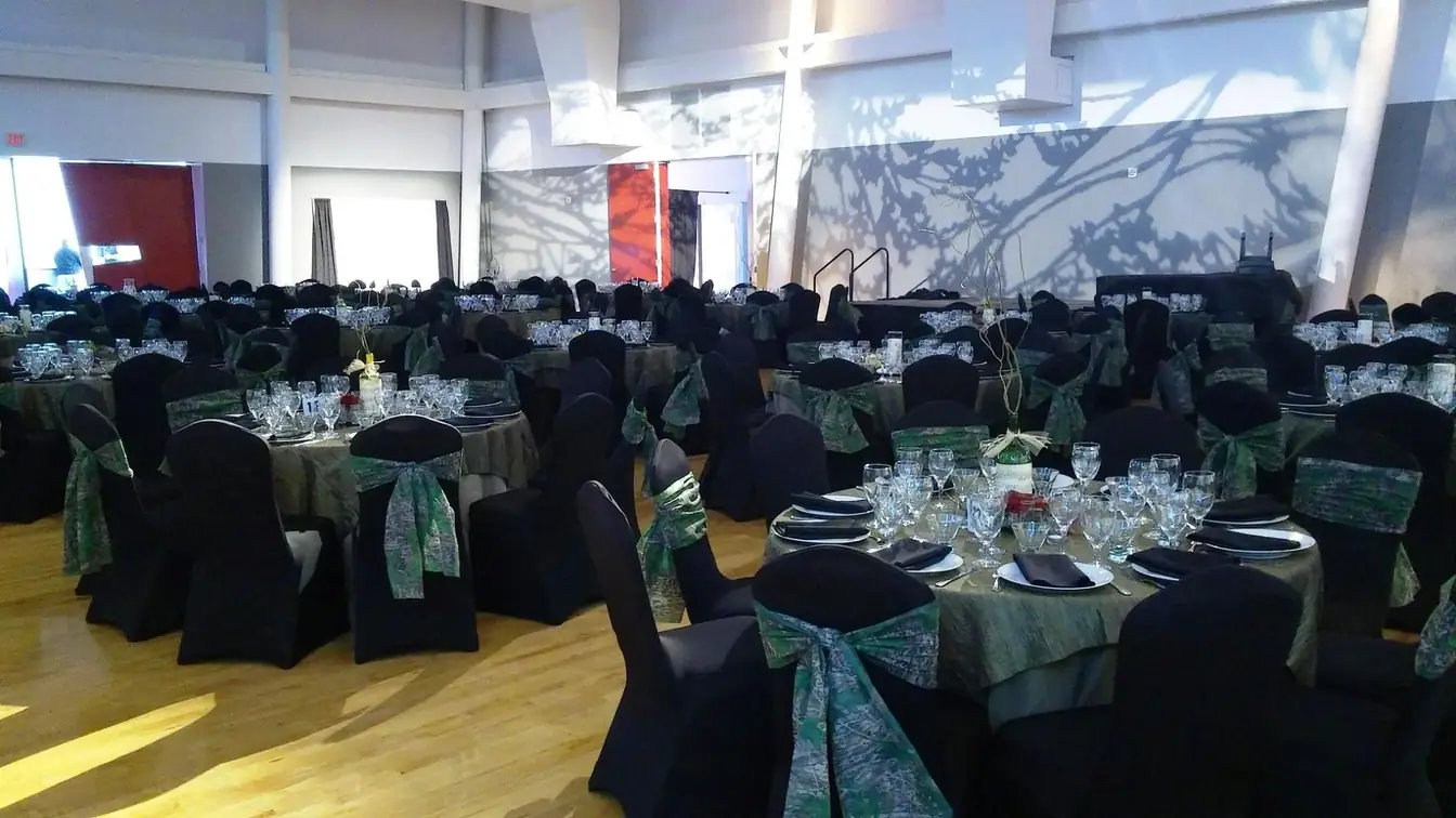 Black chair covers with green organza sashes at tables set with candelabras