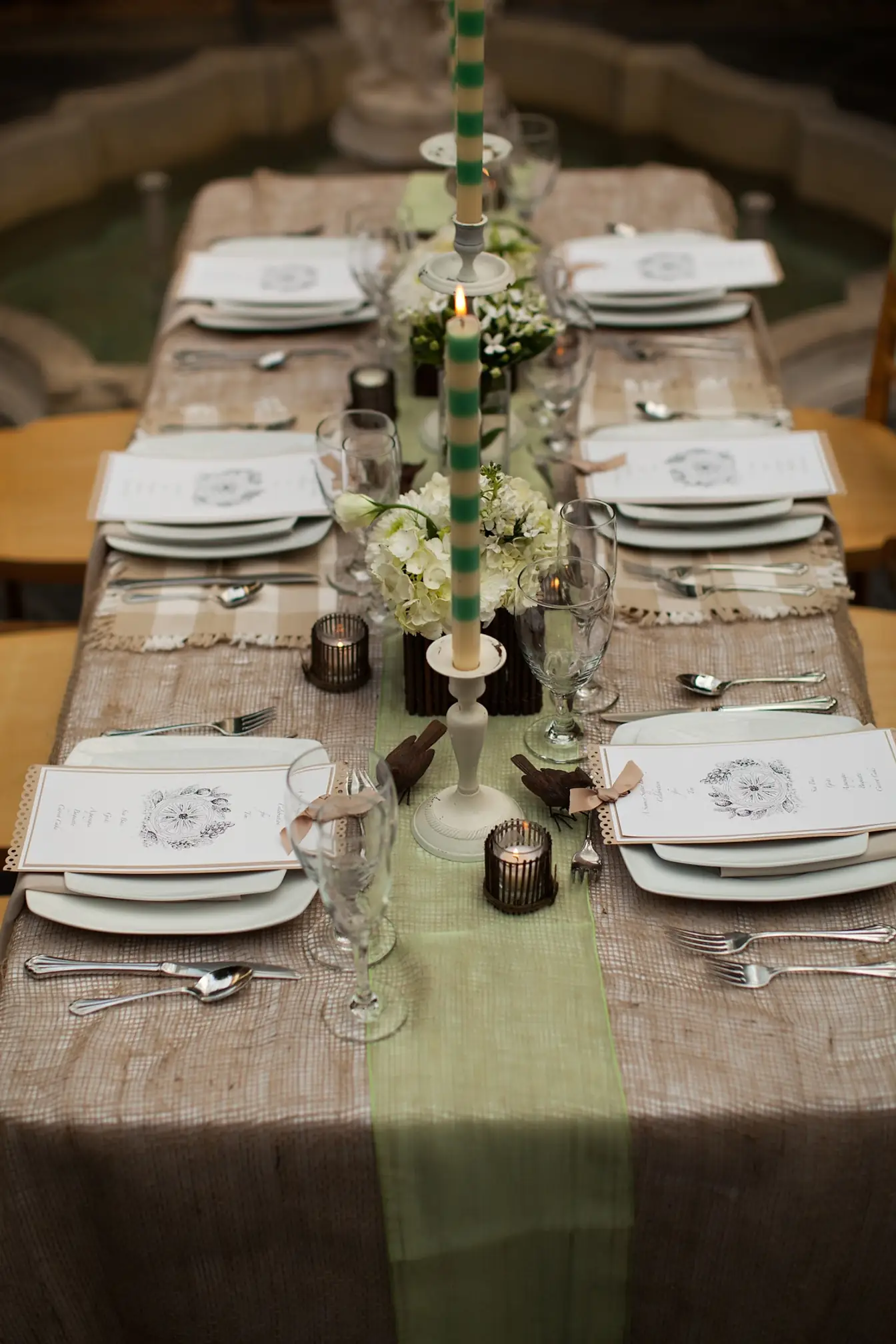 Long farm table with green runner, taper candles, and printed menus at each setting
