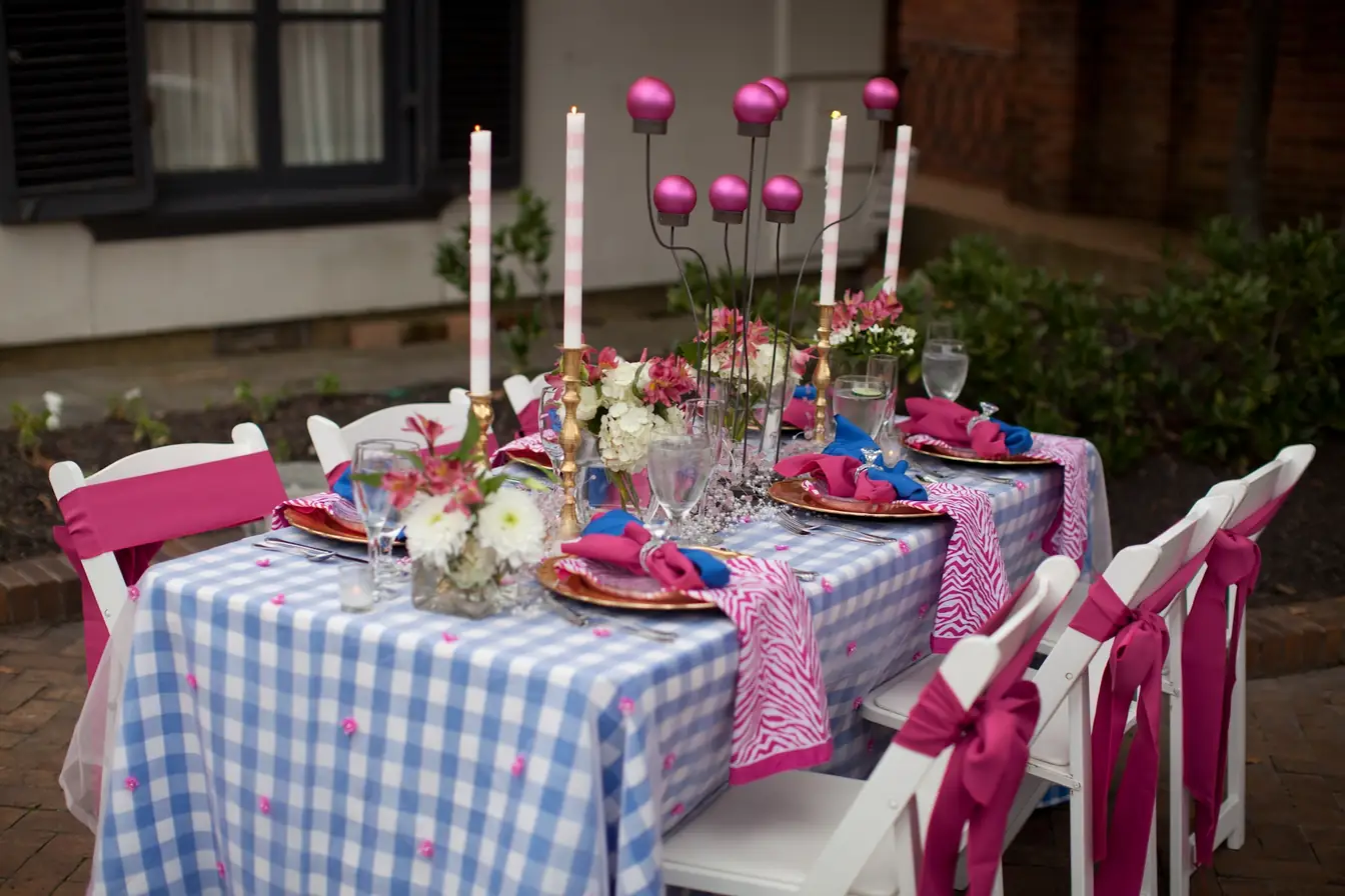 Blue gingham tablecloth with fuchsia zebra napkins and gold charger plates outdoors