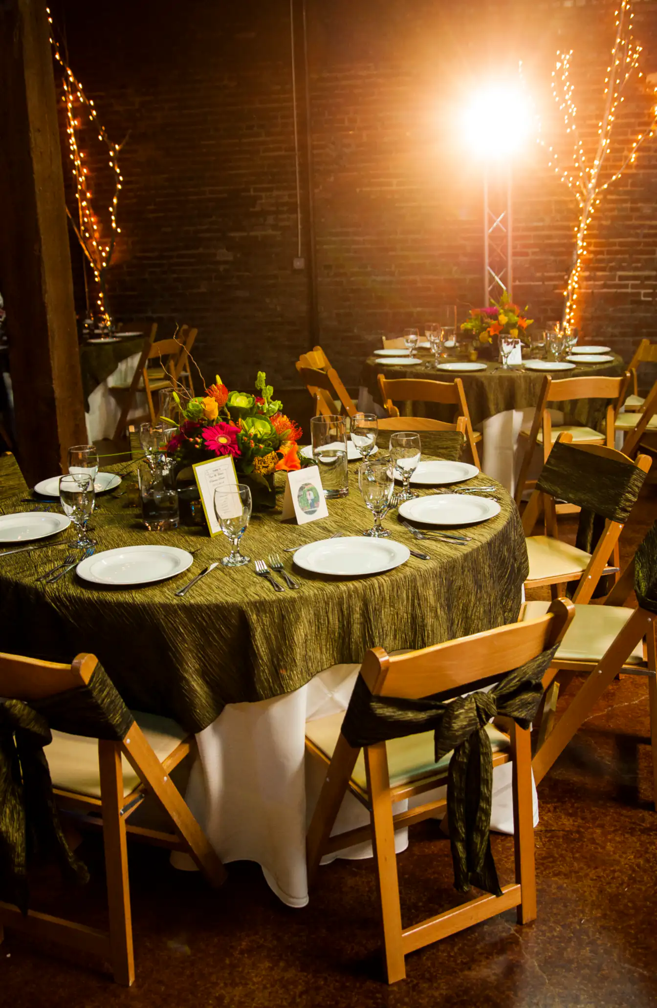 Olive crinkle tablecloth set with white china and glassware, wood folding chairs around