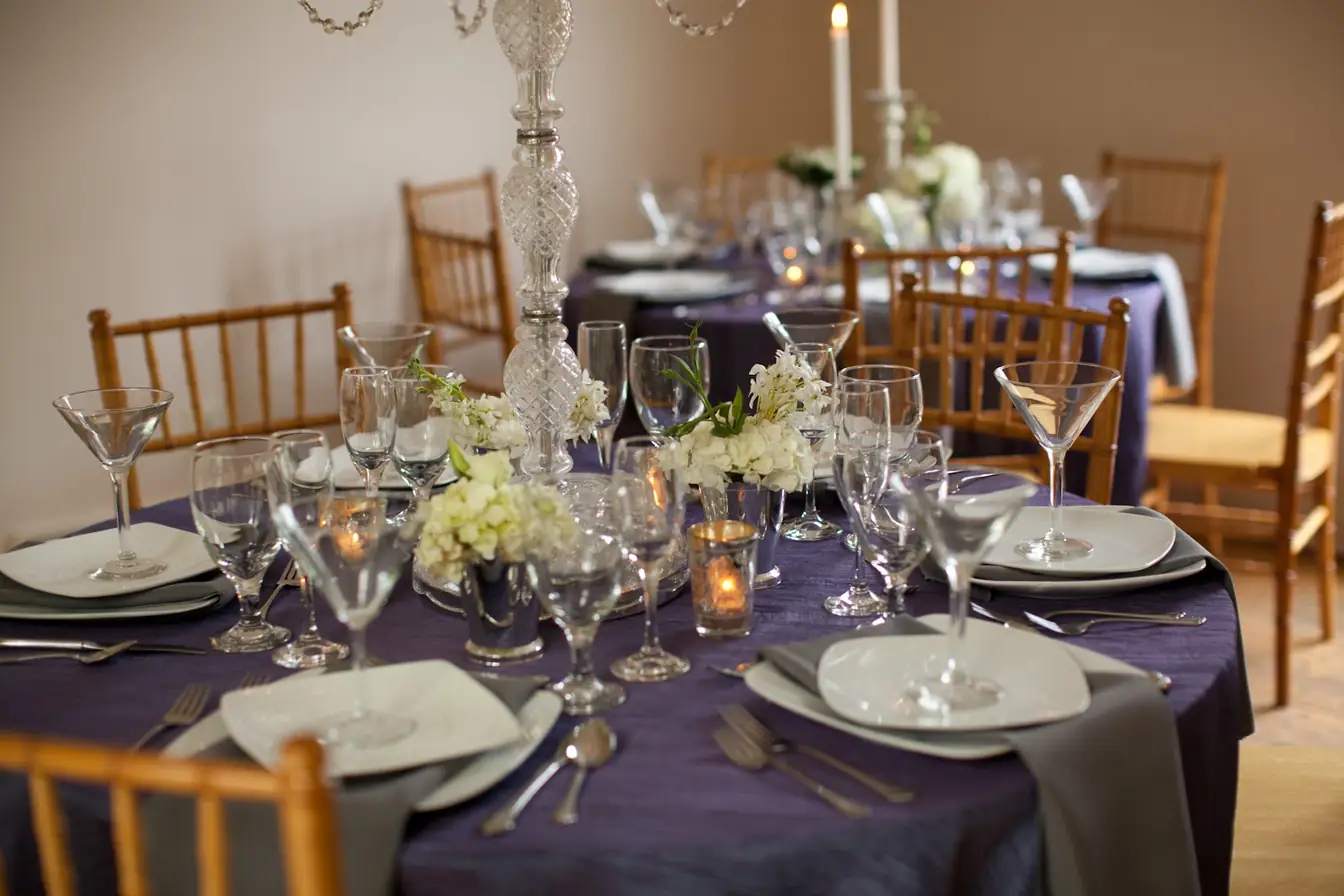 Purple linens set with martini glasses, stemware, and white floral centerpieces