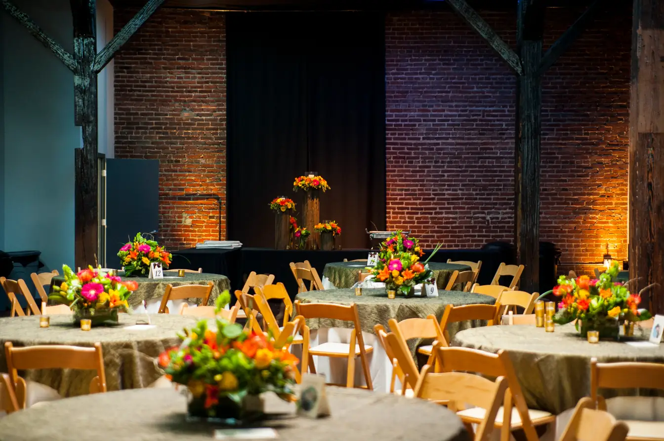 Round tables with olive crinkle linens and natural-wood folding chairs at a brick warehouse wedding