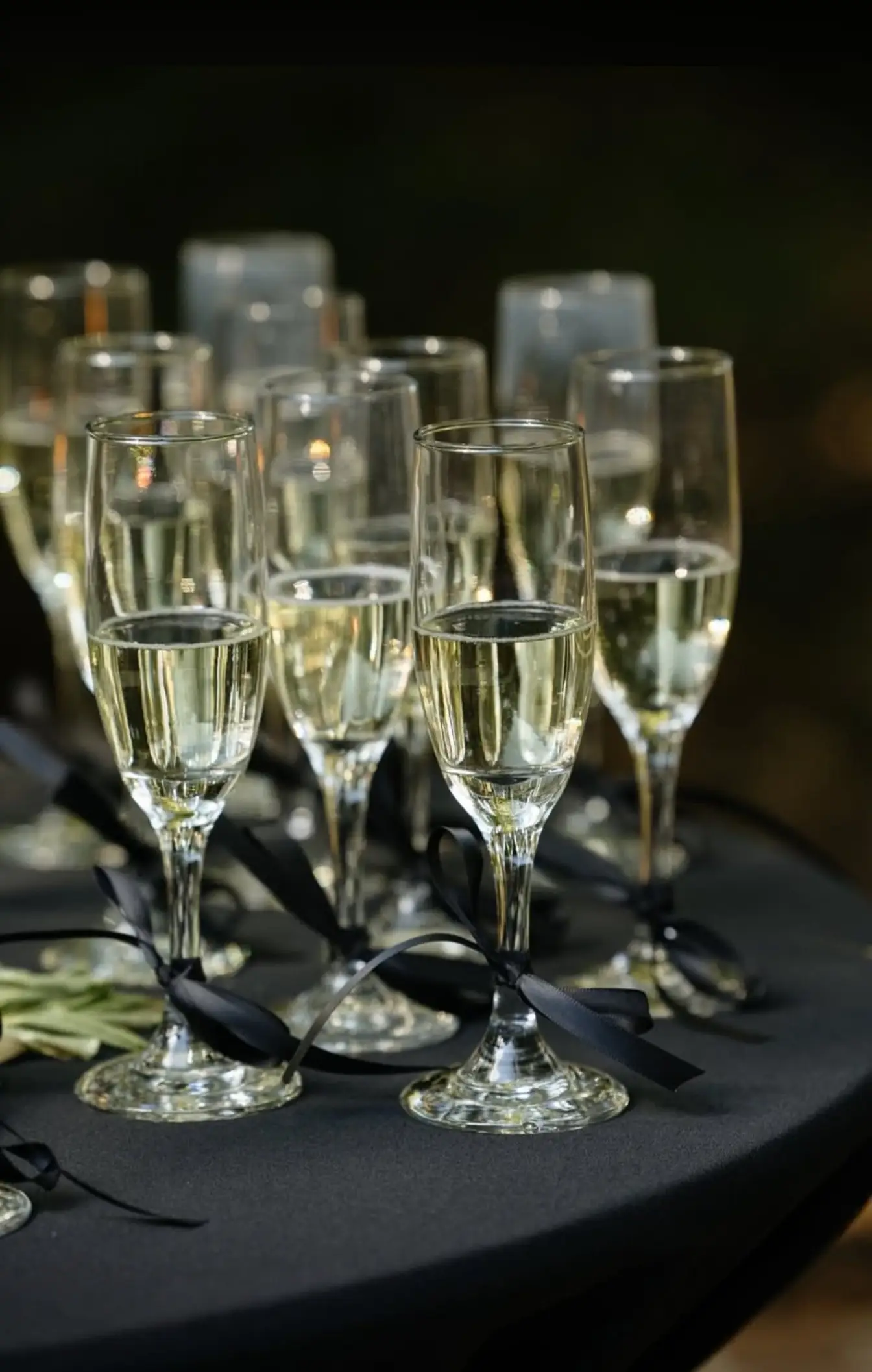 Champagne flutes tied with black satin ribbon gathered on a black-linen cocktail table