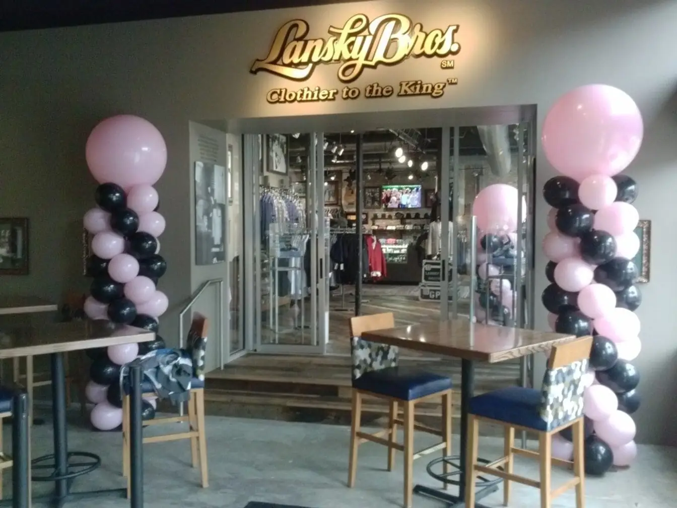 Pale pink and black balloon columns topped with jumbo pink balloons flanking a shop entrance