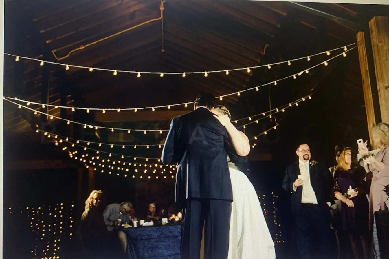 First dance beneath a canopy of bistro lights strung across a timber-framed hall